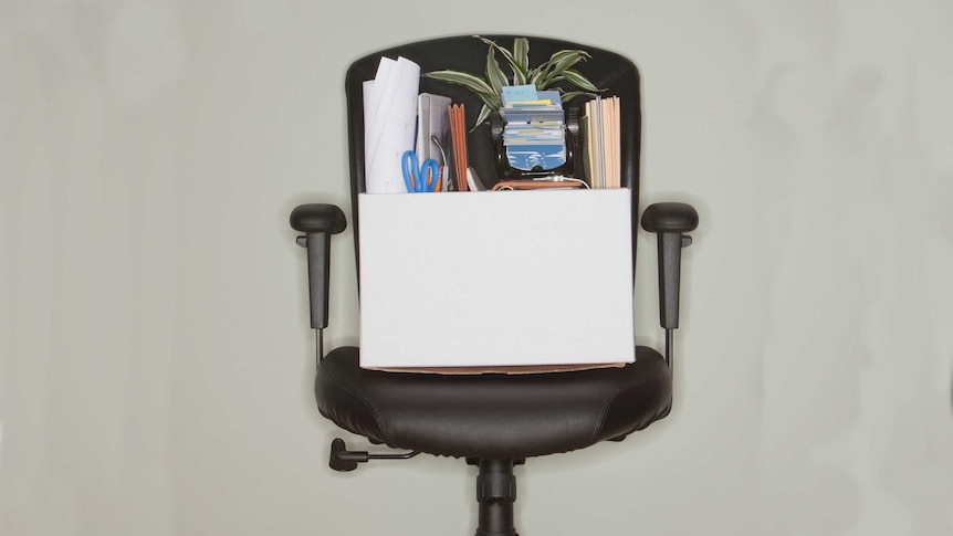 An office chair with a cardboard box of office items sitting on it.