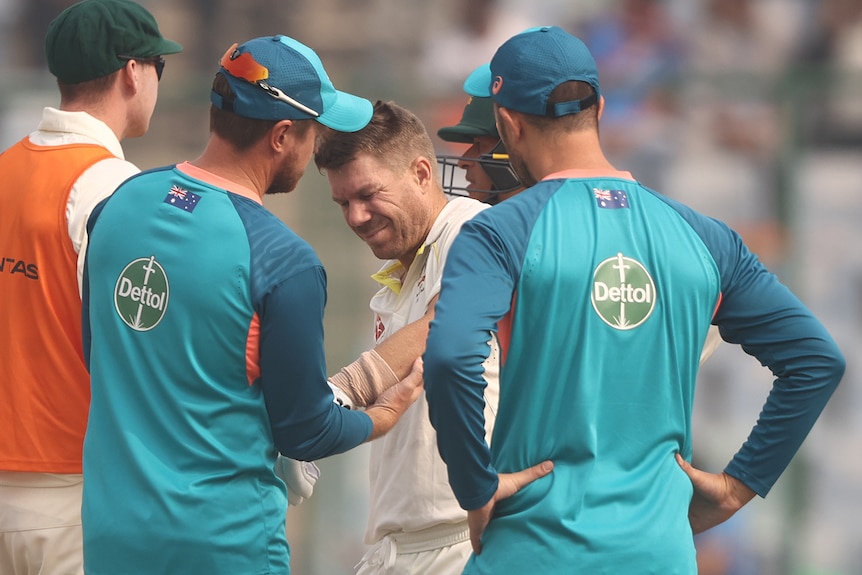 An Australian male batter receives medical attention on the field during a Test match in Delhi.
