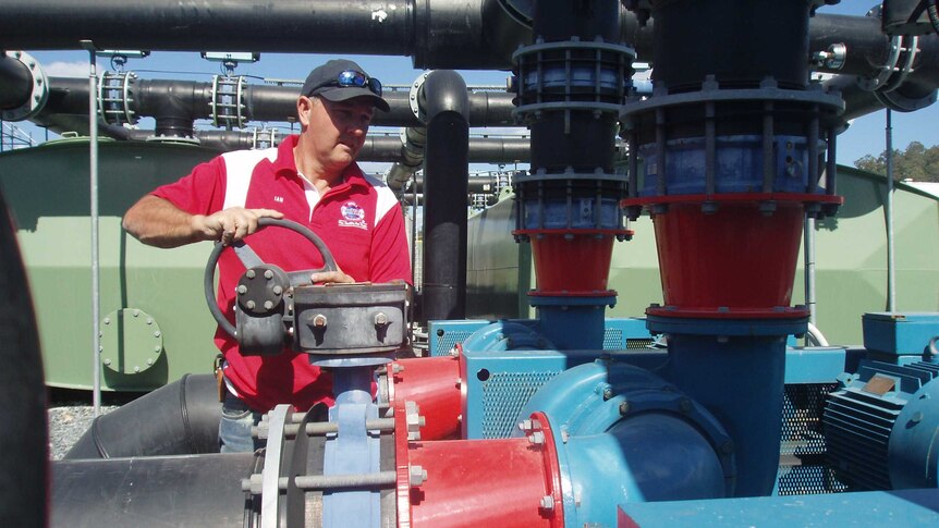 Man in red shirt with hands on the steel wheel controlling a water valve