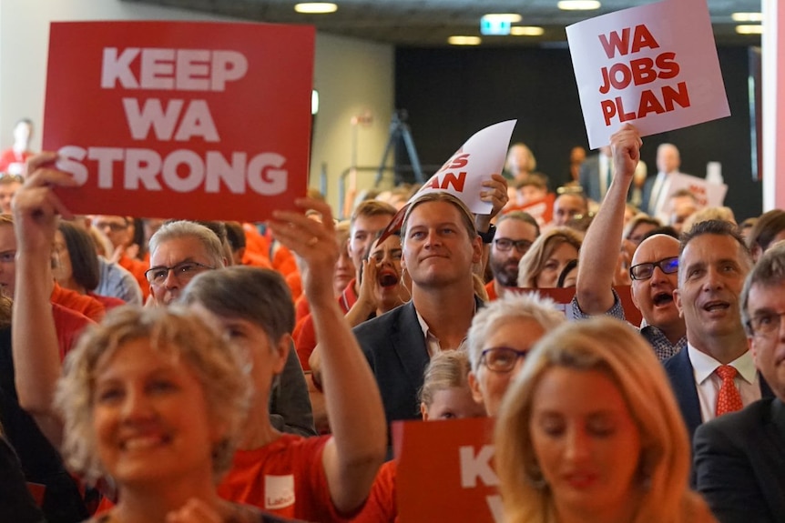 A crowd of people sit waving signs saying 'keep WA strong' and 'WA jobs plan'.