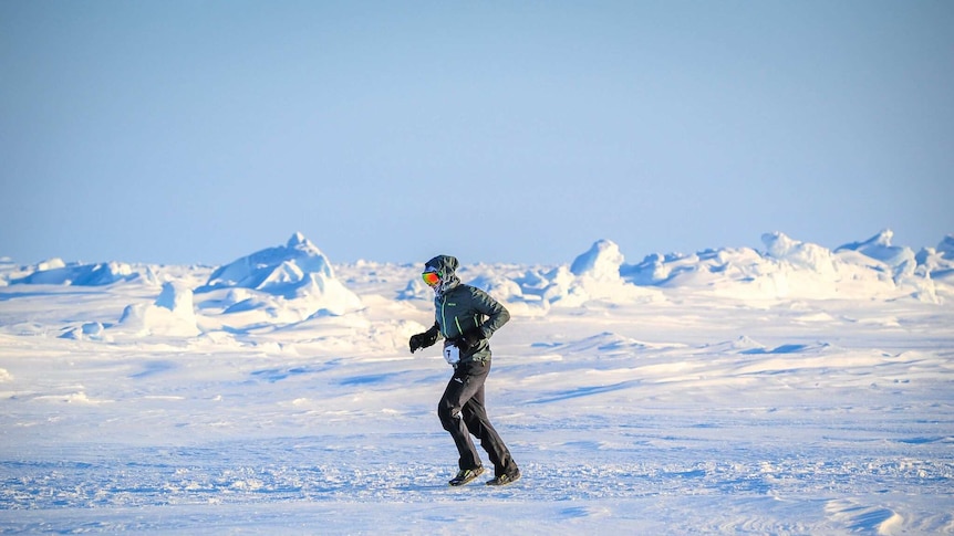 A man dressed in protective winter clothing navigates snow mounds and rough terrain during the North Pole Marathon.