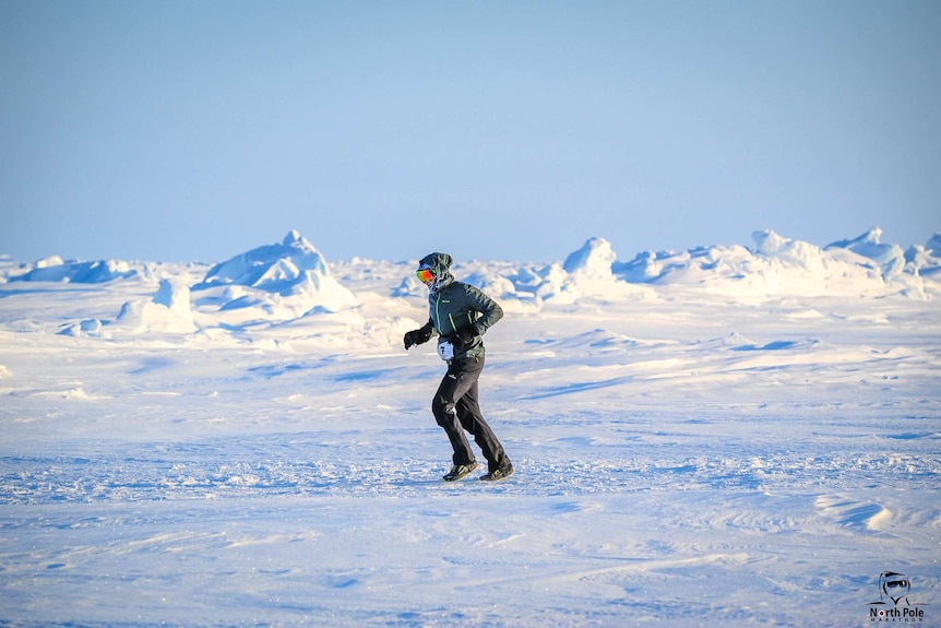 A man dressed in protective winter clothing navigates snow mounds and rough terrain during the North Pole Marathon.