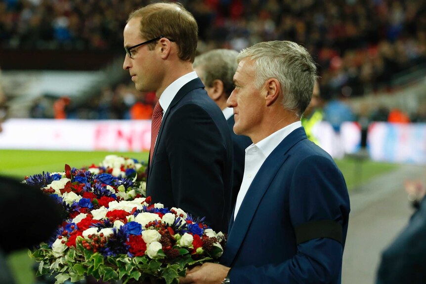 Prince William and France coach Didier Deschamps hold floral tributes.