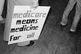 A black and white photo of a sign reading 'Medicare means medicine for all'
