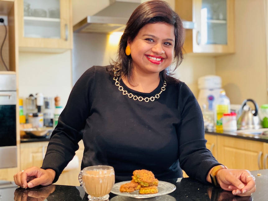 A woman smiles in front of a plate of lentil patties