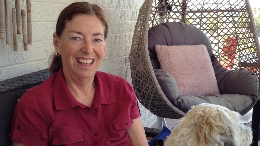 A photo of a woman smiling with a dog on her lap