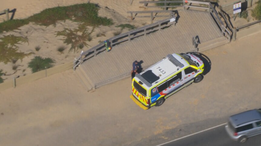 An ambulance parked in front of a beach.