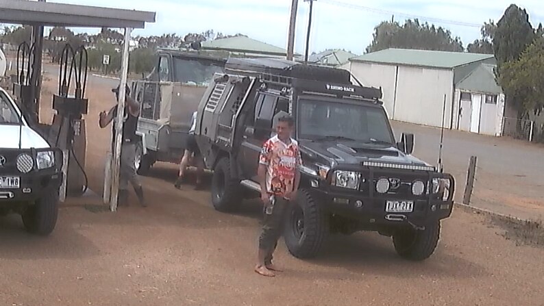 CCTV man in red shirt in front of 4WD