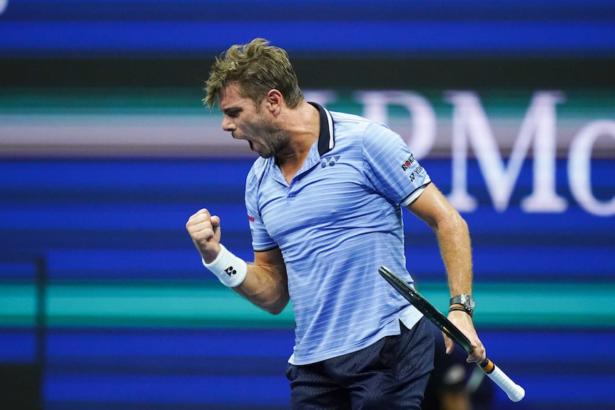 Stan Wawrinka clenches his right fist and screams, holding his racquet in his left hand