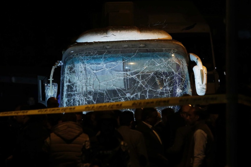 Lights are shone on the front of a tourist bus with a shattered windscreen and damaged mirrors.