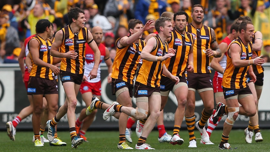 Hawthorn players run to congratulate Xavier Ellis after he kicked the opening goal.