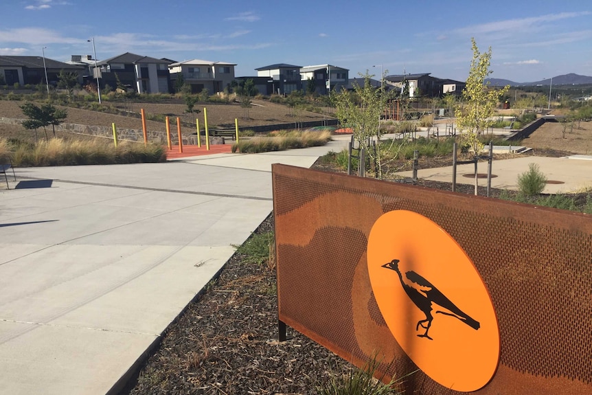 A public park in the Molonglo Valley featuring a magpie illustration on a fence. Newly completed housing in the distance.