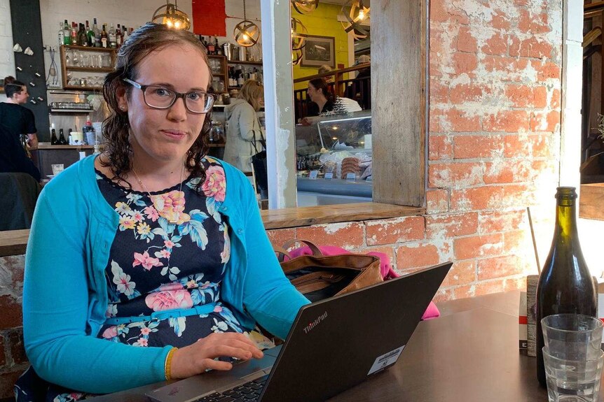 Katie Dowling sits at a cafe with her laptop open