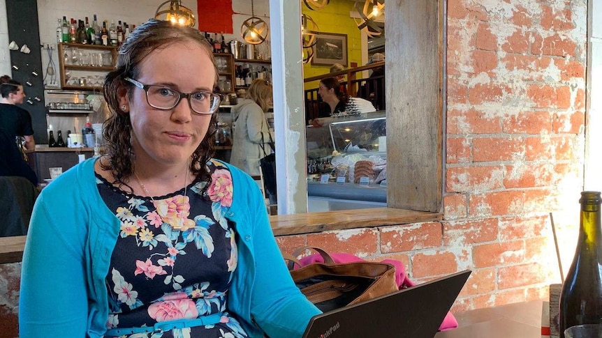Katie Dowling sits at a cafe with her laptop open