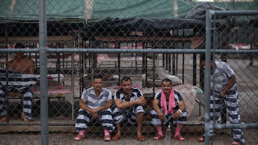 Inmates don black and white stripe uniforms with pink socks