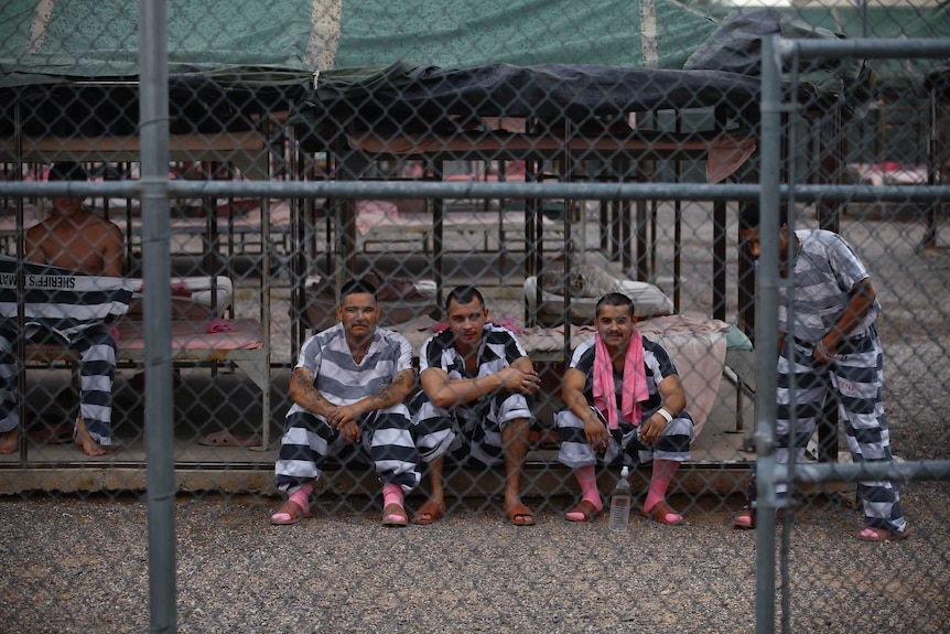 Inmates don black and white stripe uniforms with pink socks