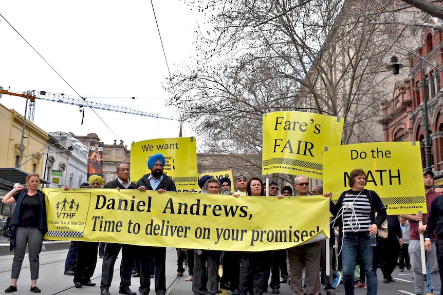 Taxi drivers march down a CBD street in Melbourne holding a large banner, as they protest against a shake-up of the industry.