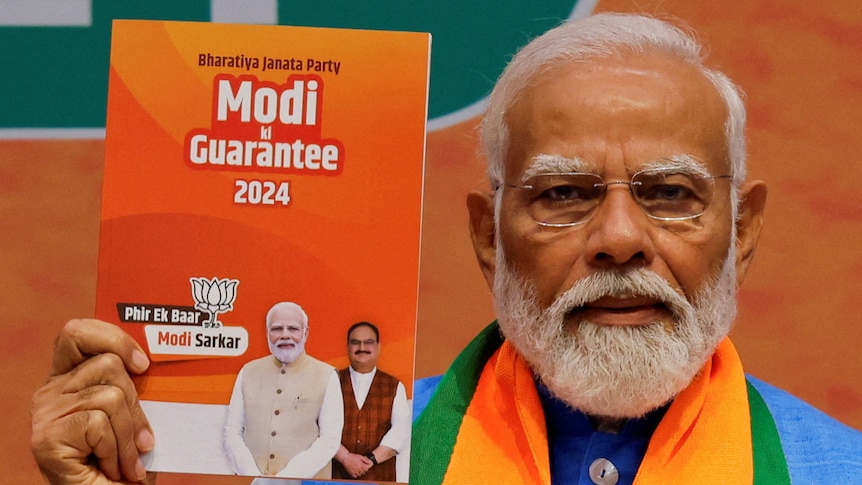 Narendra Modi holds a printed copy of his party's election manifesto titled "Modi guarantee 2024".