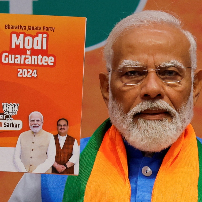 Narendra Modi holds a printed copy of his party's election manifesto titled "Modi guarantee 2024".