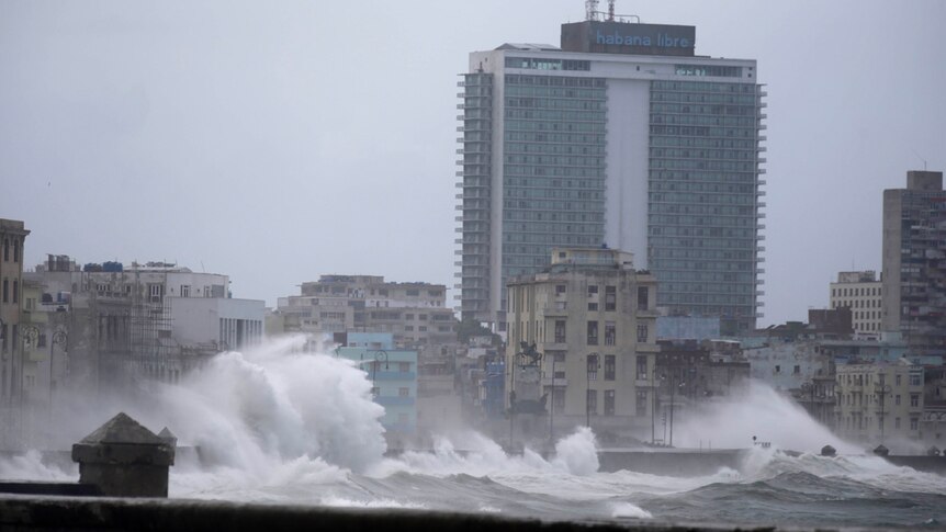 Waves surge over a sea wall in Havana, Cuba, almost reaching the height of some of the buildings in the city.