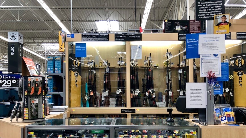 guns, rifles and gun accessories are shown behind glass at a walmart store