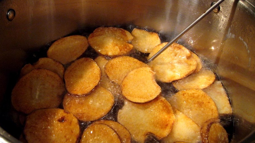 Potato crisps simmering in a pot of oil.