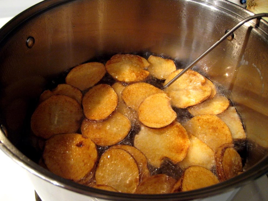 Potato crisps simmering in a pot of oil.