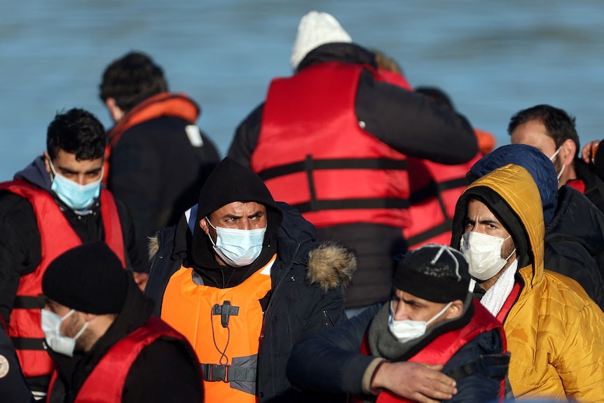 People in life vests, with the sea in the background