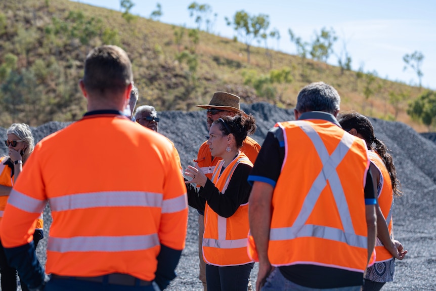 A group of people in high-vis orange vests with a woman in the middle.