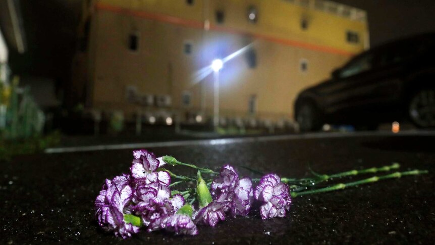 Purple flowers are laid at night following a fire in front of Kyoto Animation building in Kyoto