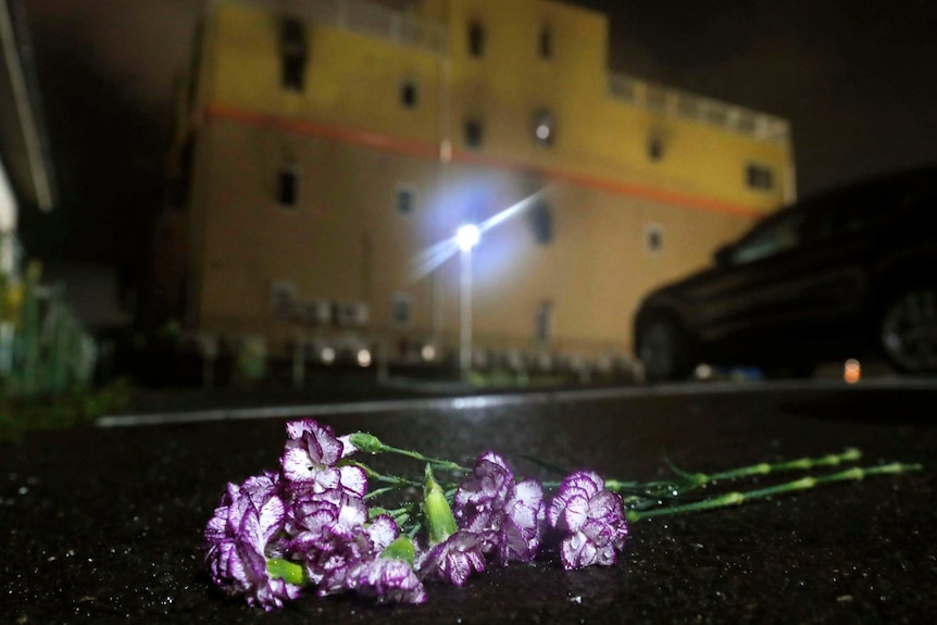 Purple flowers are laid at night following a fire in front of Kyoto Animation building in Kyoto