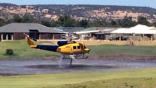 A helitac takes water from a lake in Ellenbrook to fight fires in Bullsbrook