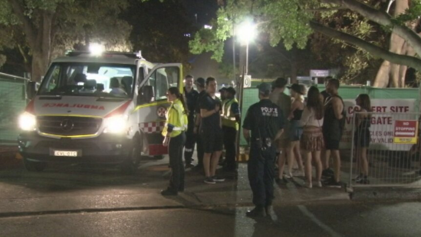 Ambulance officers take a 23-year-old woman to hospital after a suspected drug overdose at Field Day