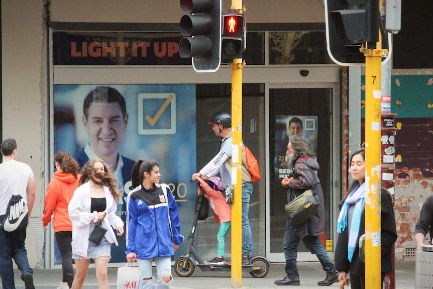 Basil Zempilas posters hang in a Northbridge shop window as people cross the street in the foreground