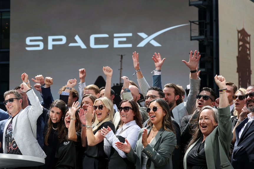 People cheer on balcony under SpaceX sign