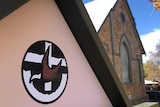 A church building with a logo on the front featuring a cross