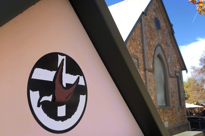 A church building with a logo on the front featuring a cross