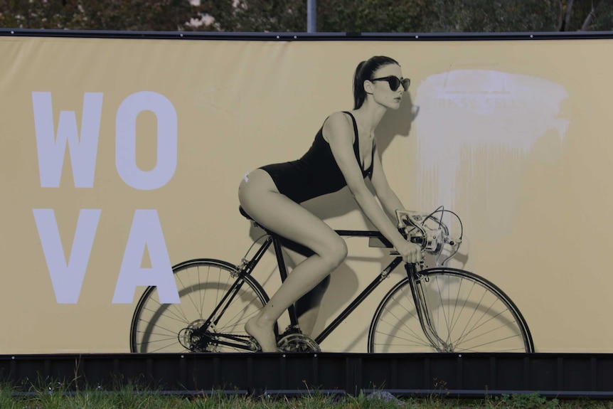 A woman in a swimsuit riding a bike on an advertising billboard.