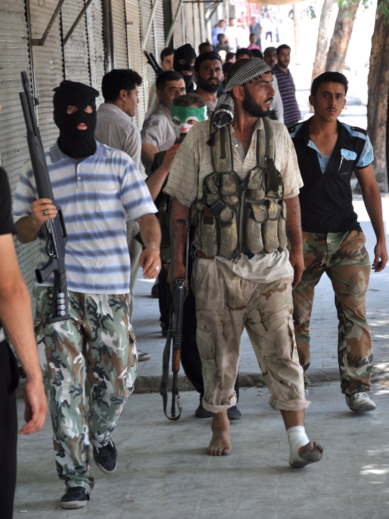 Syrian opposition fighters march through the Shaar district police station in Aleppo.