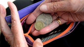 Hands put Australian coins into a wallet.