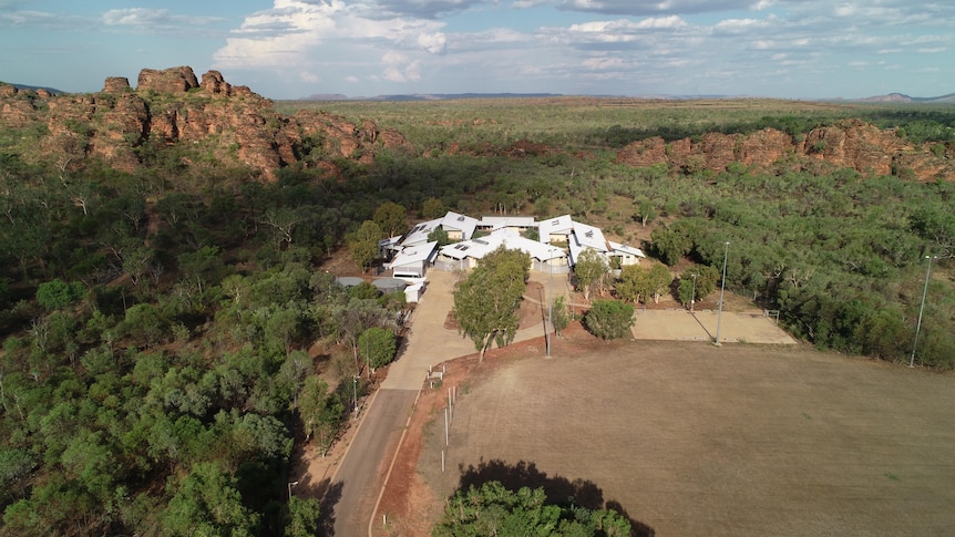 An aerial shot of a hostel nestled in the bush between red rock landscape