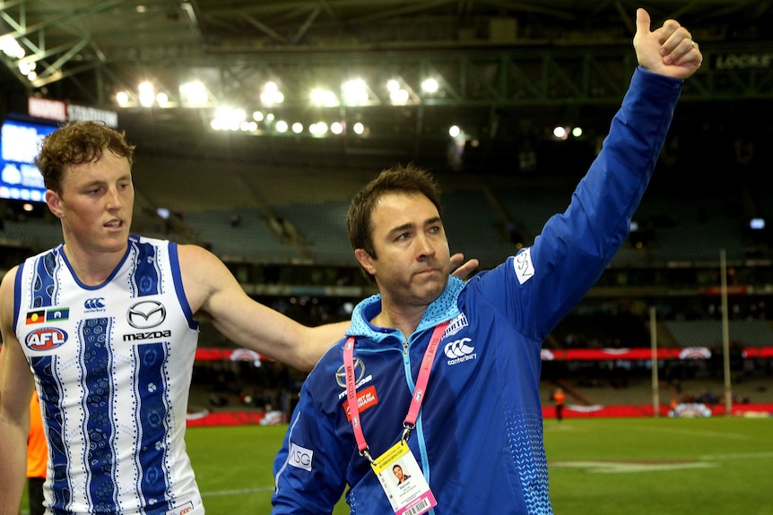 Brad Scott raises his left arm and gives the thumbs up to the Docklands crowd.
