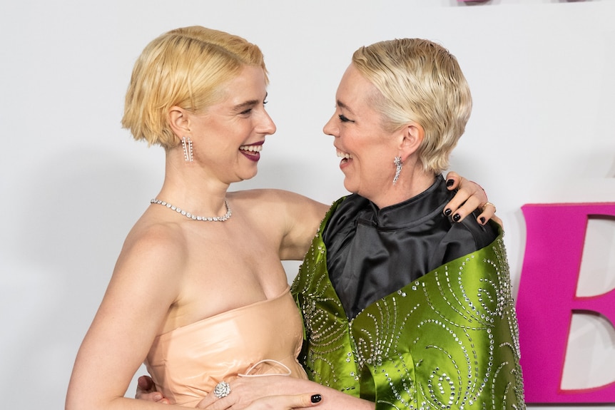 Two women with peroxide blonde hair look at each other affectionately on the red carpet