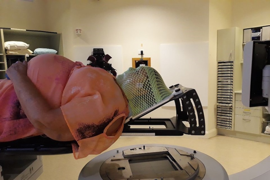 A woman lies in hospital before radiation therapy.