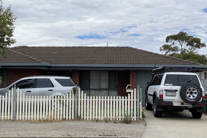 A suburban house with a sedan in the front yard and a four-wheel-drive in the car port.