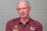 Wayne Bennett in a Queensland Rugby League polo shirt in front of a brick wall.