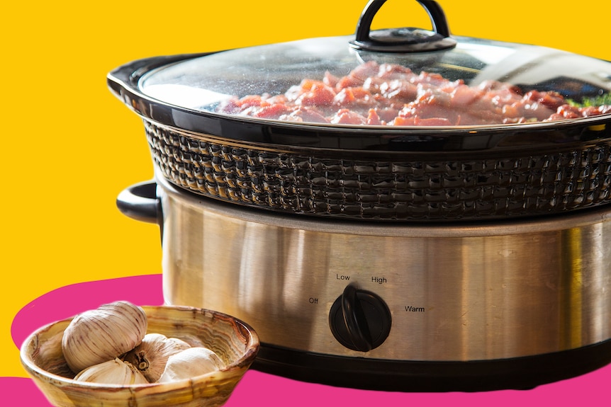 A generic image of a slow cooker cut out against a yellow background with a pink shadow. A bowl of garlic is in front.