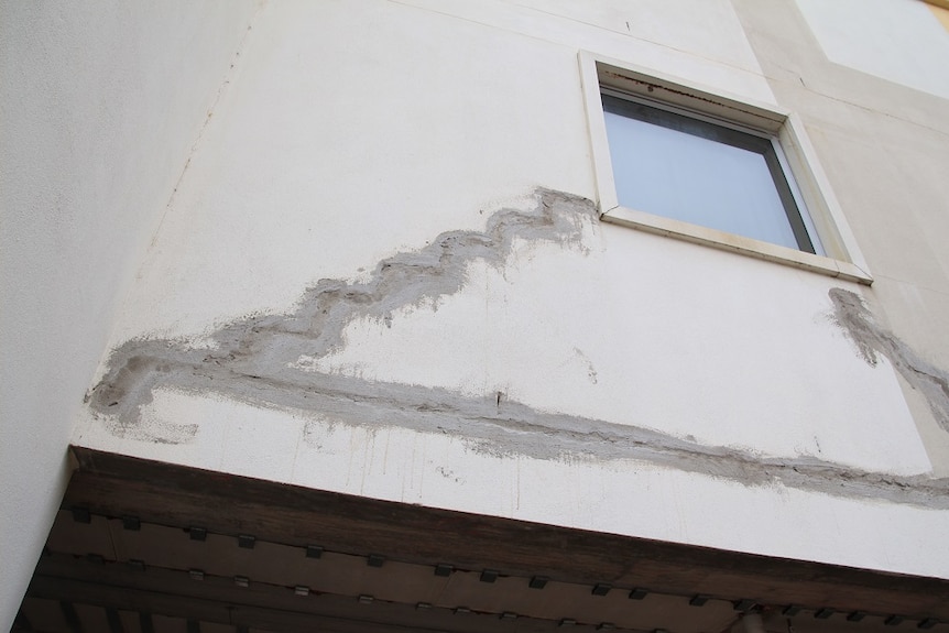 Several cracks on the exterior of the building's second floor.