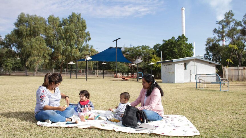 Amita Chanaria and her daughter Myra (left and second from left) sit with friends in a Mount Isa park.