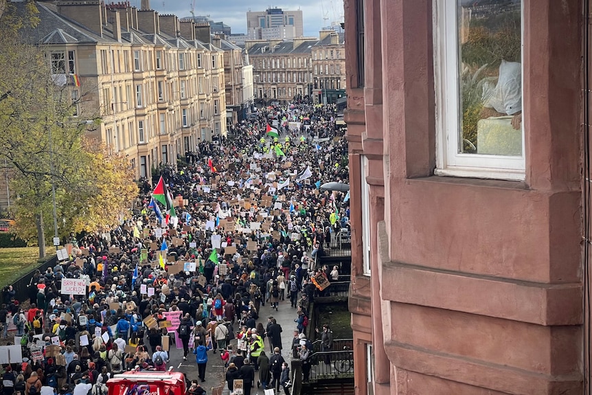 Ripresa aerea di migliaia di manifestanti che camminano in una strada cittadina nel Regno Unito.